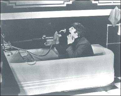 John Lennon in A Hard Day's Night: John sits in the tub in a outtake from the Beatles first film. The shots of John in the bathtub which made it into the movie had him clad in black swim trunks.